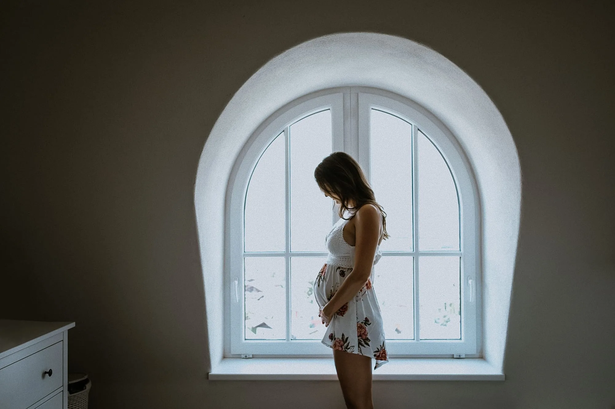 Babybauch Homestory Tirol – Silhouette am Bogenfenster