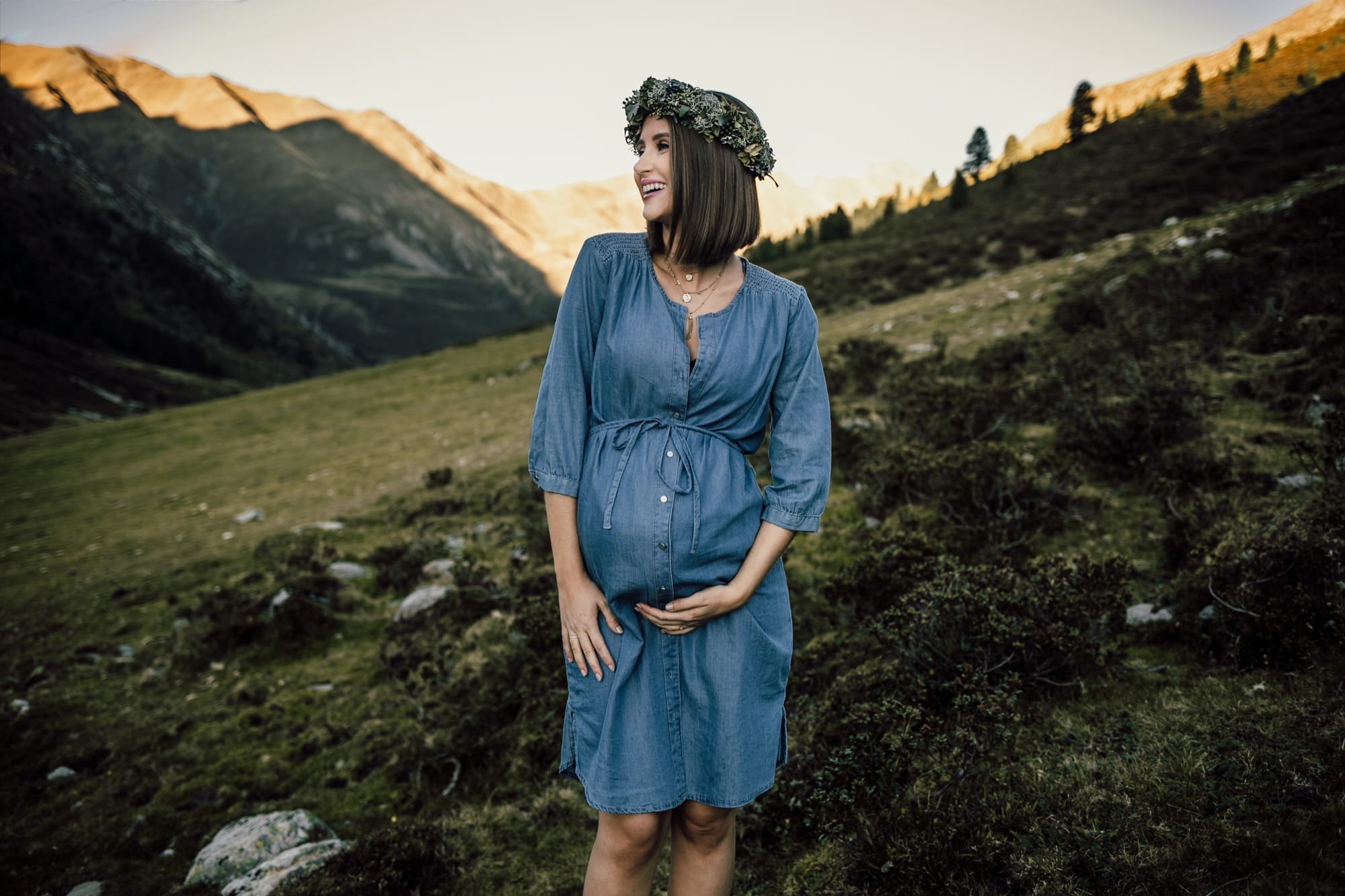 Babybauchfotografie Tirol – Schwangere im blauen Kleid auf der Almwiese
