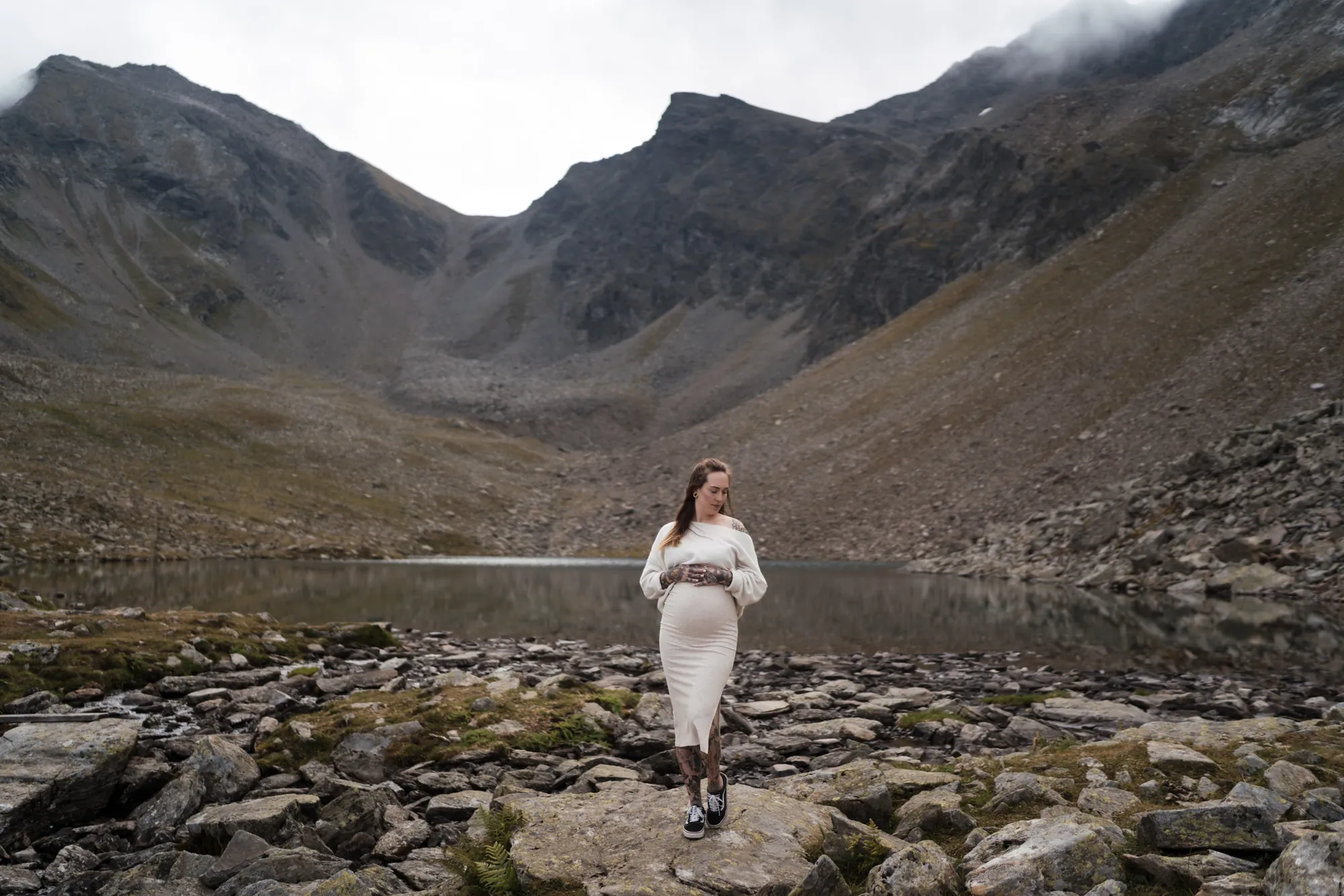 Babybauchfotografie Tirol – Schwangere am Bergsee im Strickkleid