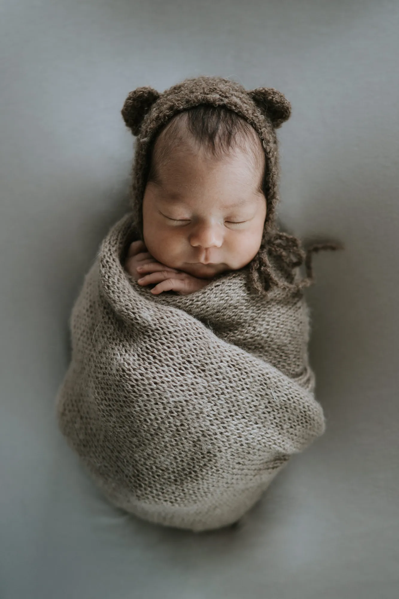 Neugeborenenfotografie Innsbruck – gewickeltes Baby mit Bärchenmütze