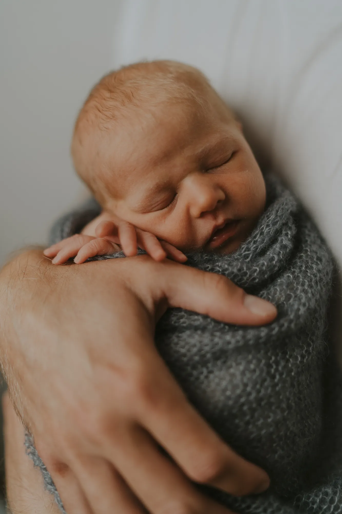 Newborn Fotografie Tirol – Neugeborenes geborgen auf Papas Arm