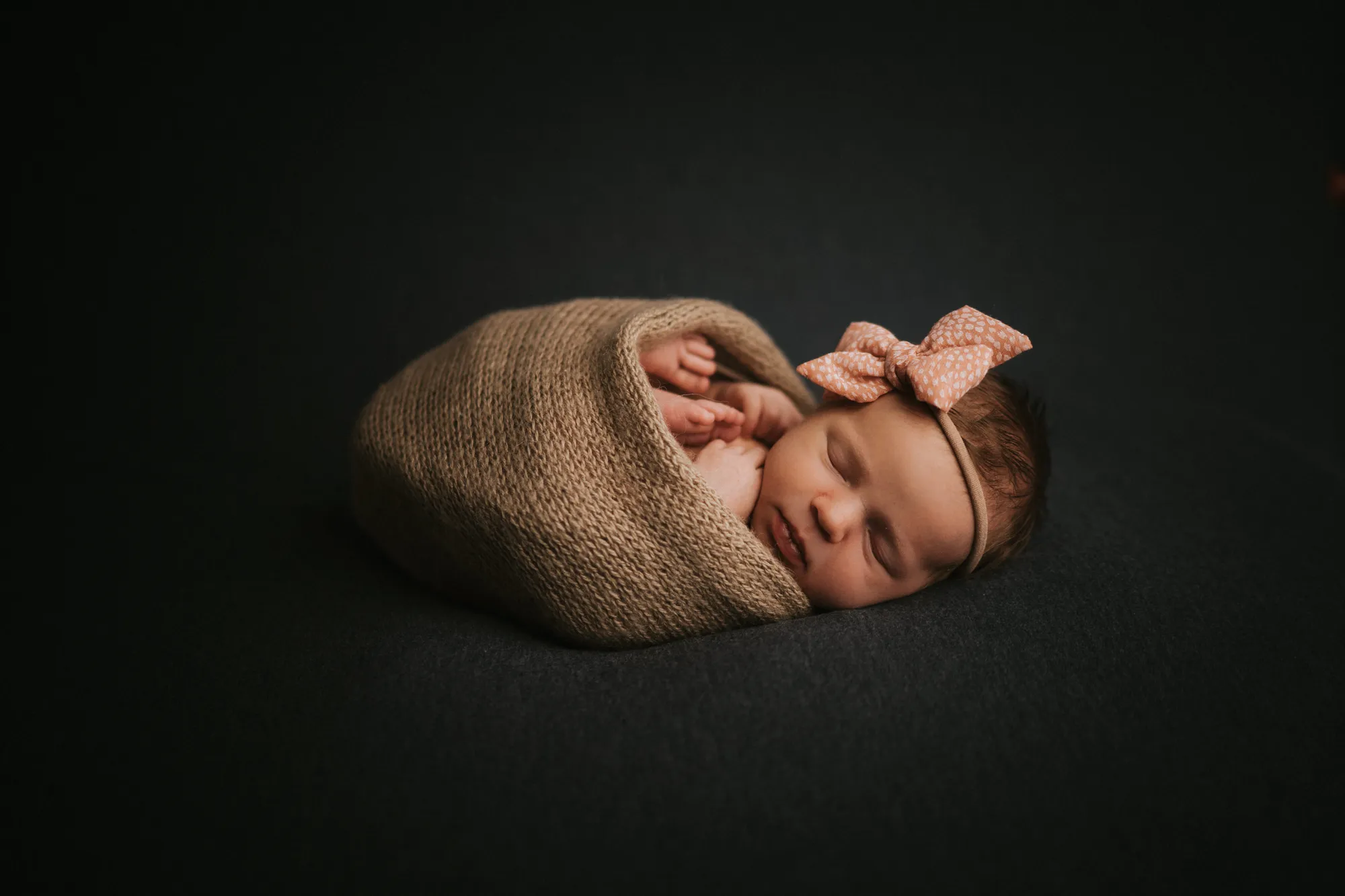 Newborn Shooting Tirol – Neugeborenes mit Schleife in Strickdecke