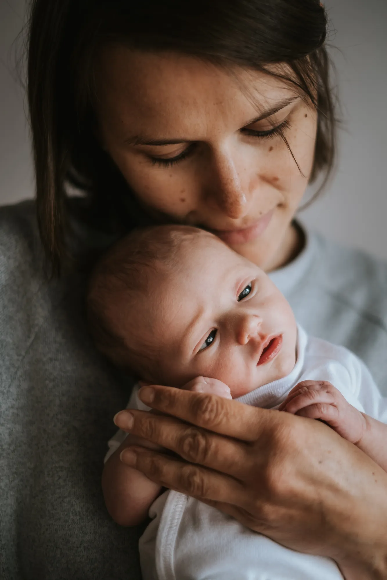Newborn Shooting Tirol – Mama kuschelt mit wachem Neugeborenen